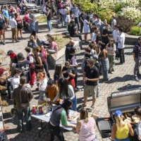 Dans la cour intérieure du cégep, on voit une foule de gens, à la fois des étudiants et des membres du personnel, qui viennent prendre des hot-dogs, qui discutent ou prennent le soleil, dans une ambiance de rentrée scolaire et de retrouvailles avec des amis.