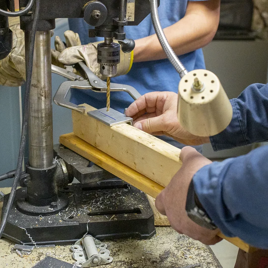 Des collaborateurs percent un morceau de bois.