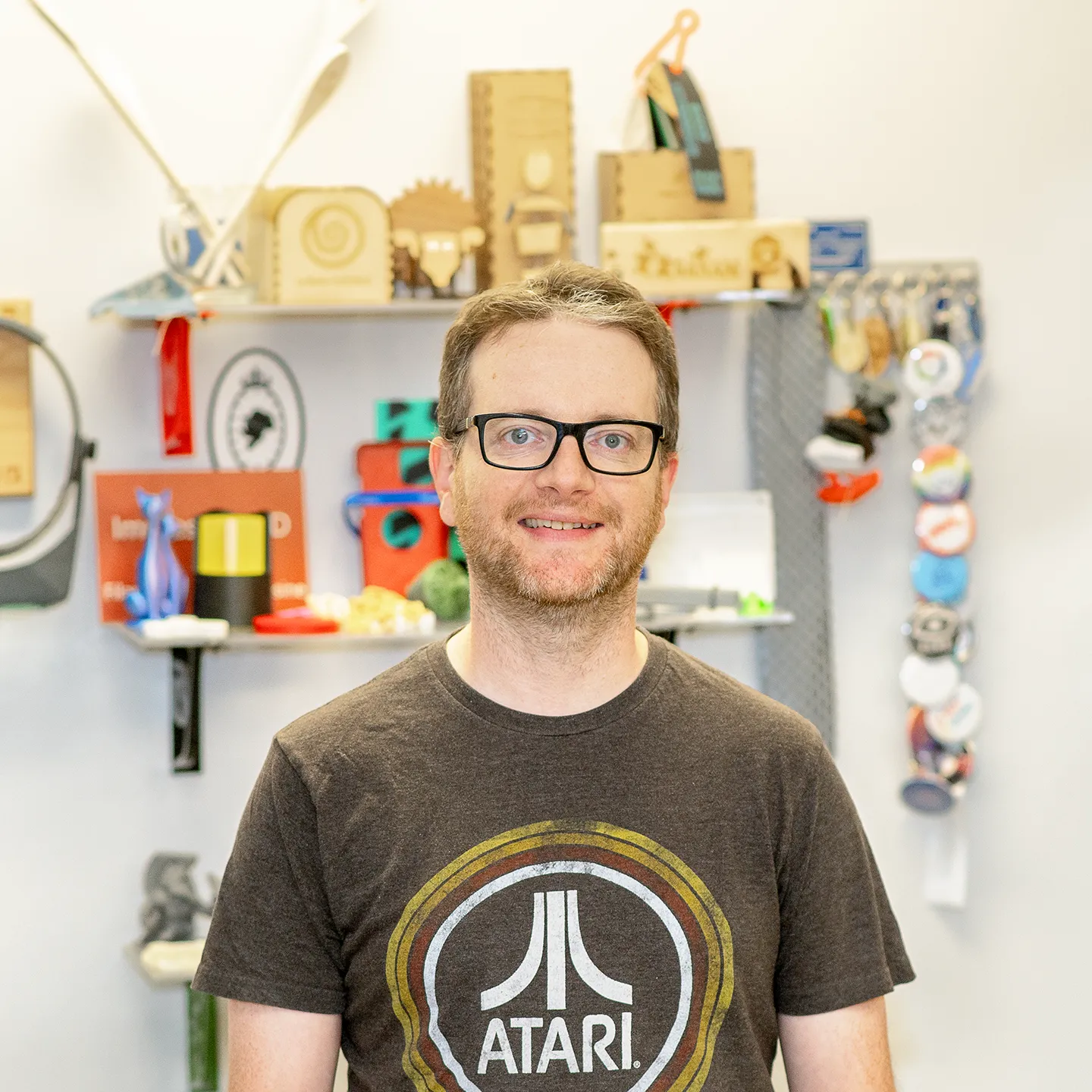 François Truchon, le coordonnateur du Fablab, pose devant la caméra. Des objets fabriqués dans ce laboratoire de création numérique sont sur des étagères derrière lui.