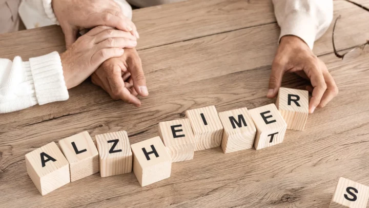 Des mains placent des cubes où apparaissent les lettres du mot Alzheimer
