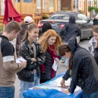 Des étudiantes et étudiants animent des kiosques interactifs au centre-ville de Matane dans le cadre du Park(ing) Day et discutent avec des gens qui viennent voir leur installation citoyenne.