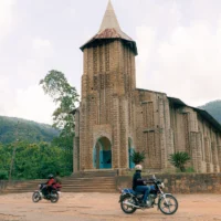 Des personnes togolaises en moto devant une église.