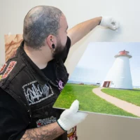 Une personne portant des gants blancs accroche au mur des photos dans le Département de photographie.